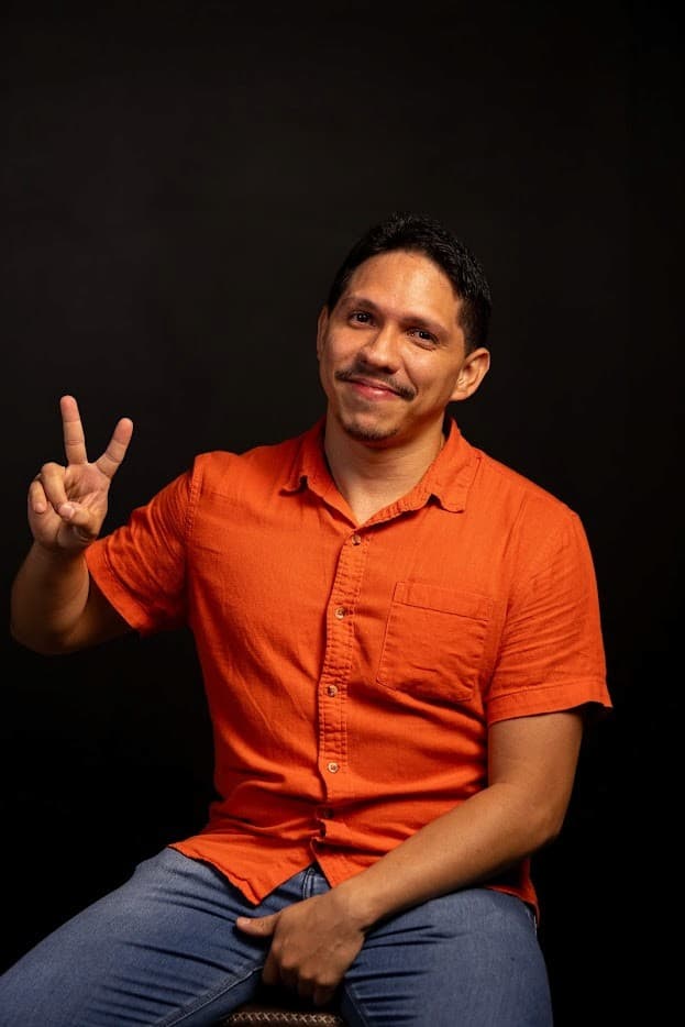 Hermano Reis de camisa laranja fazendo sinal de paz